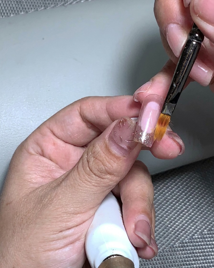 Una mano posta allinterno di una lampada UV per polimerizzare lapplicazione della foglia oro.