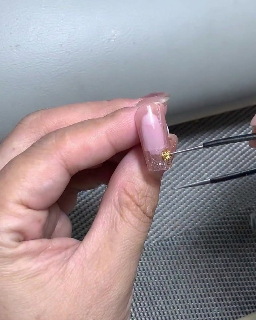 Primo piano di una mano che usa una pinzetta per posizionare delicatamente un adesivo curvo per French tip.