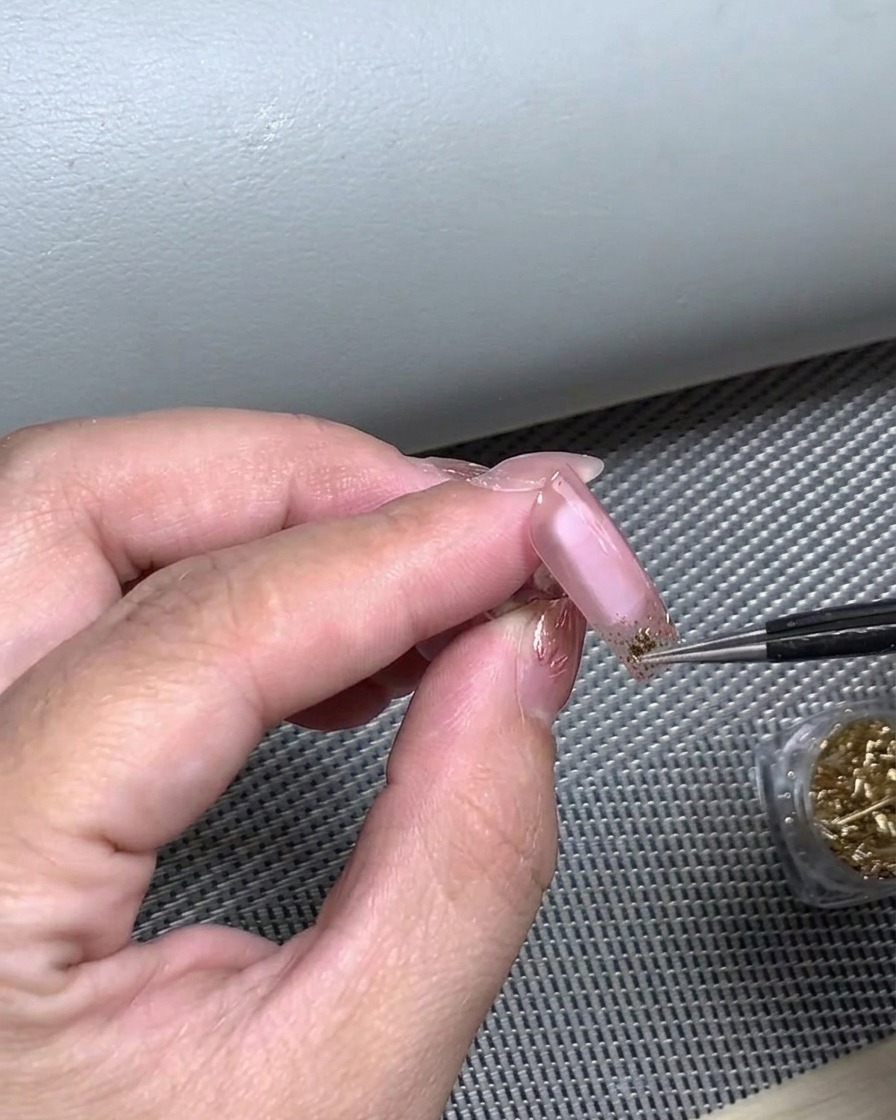 Un dito che preme su un adesivo per French tip per garantirne ladesione completa al letto ungueale.