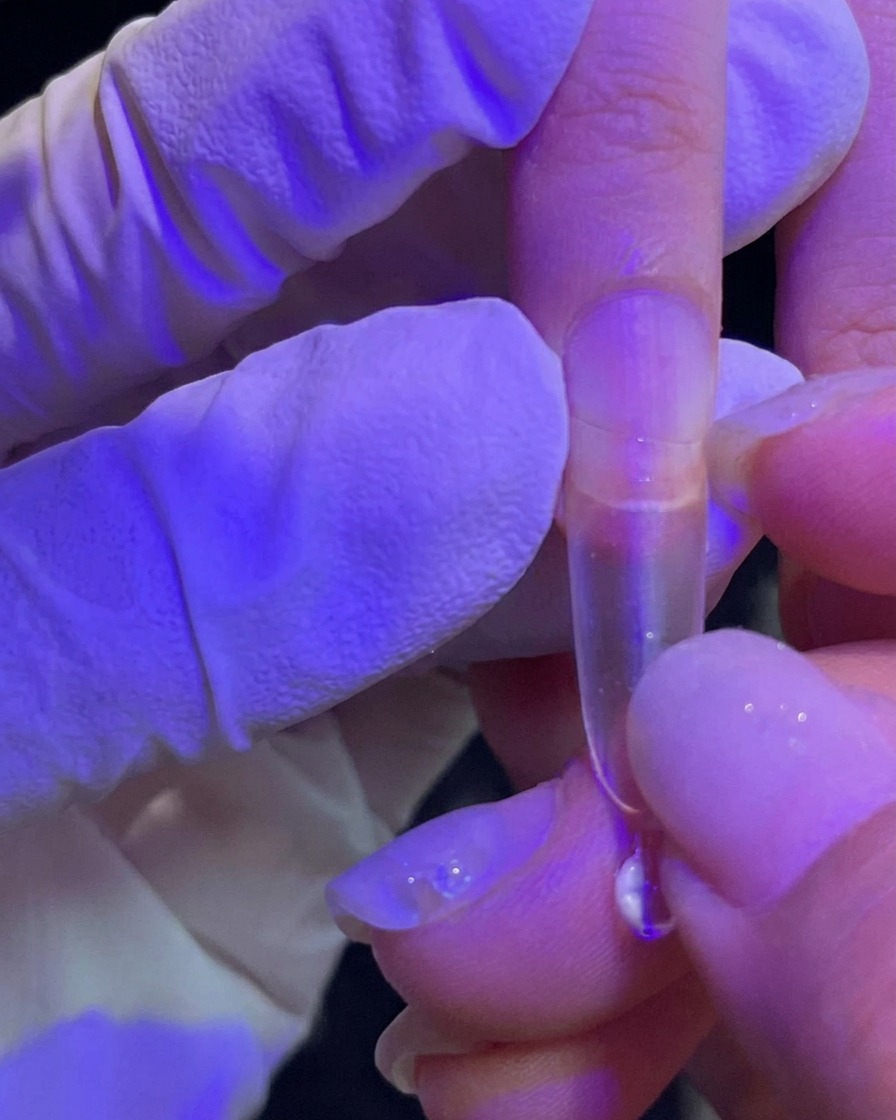 Una mano che applica una tip trasparente su ununghia naturale.