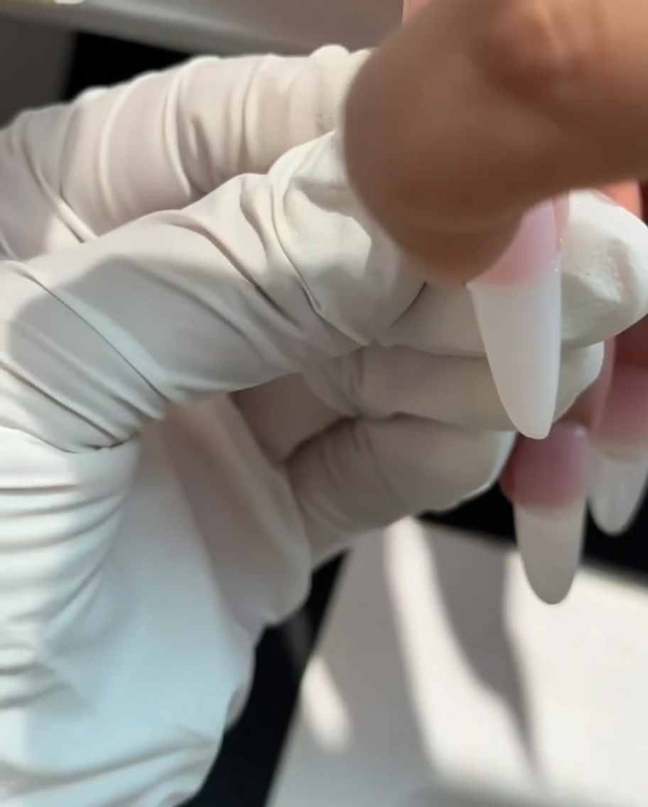 Una spugnetta usata per picchiettare gel bianco latte sulla punta dellunghia per creare un effetto ombré.