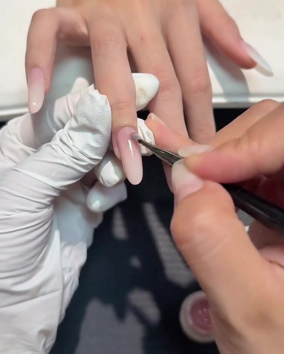Un pennellino che applica uno strato sottile di gel nude sopra la sfumatura bianco latte.