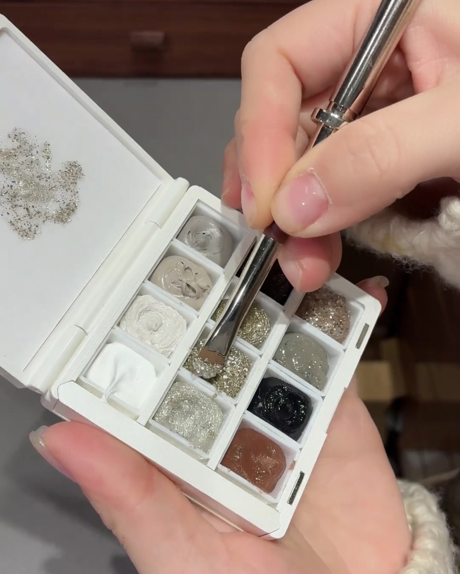 Primo piano di un pennello che sfuma il glitter argento sullunghia per creare un effetto gradiente liscio.