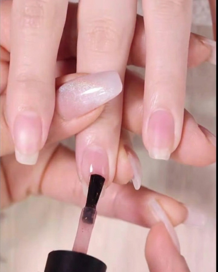 Un pennello applica il gel color ambra scuro sul terzo superiore dellunghia.