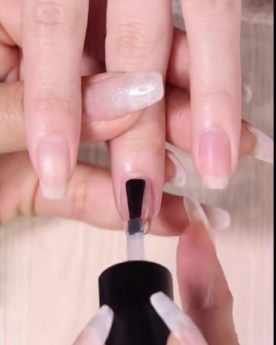 Applicazione di un top coat lucido e trasparente sullunghia completata.