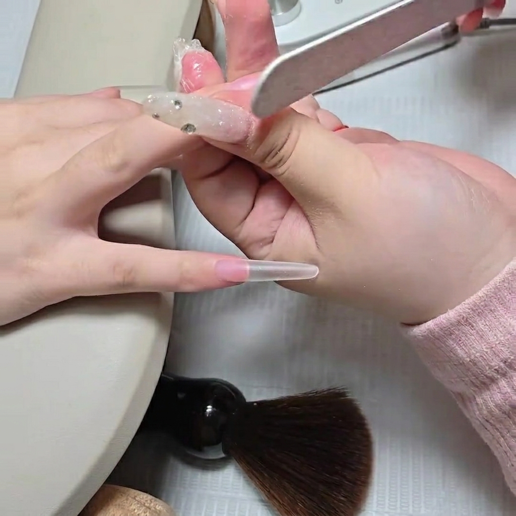Una tecnica che usa una lima manuale per sfumare la giunzione della tip a stiletto trasparente.