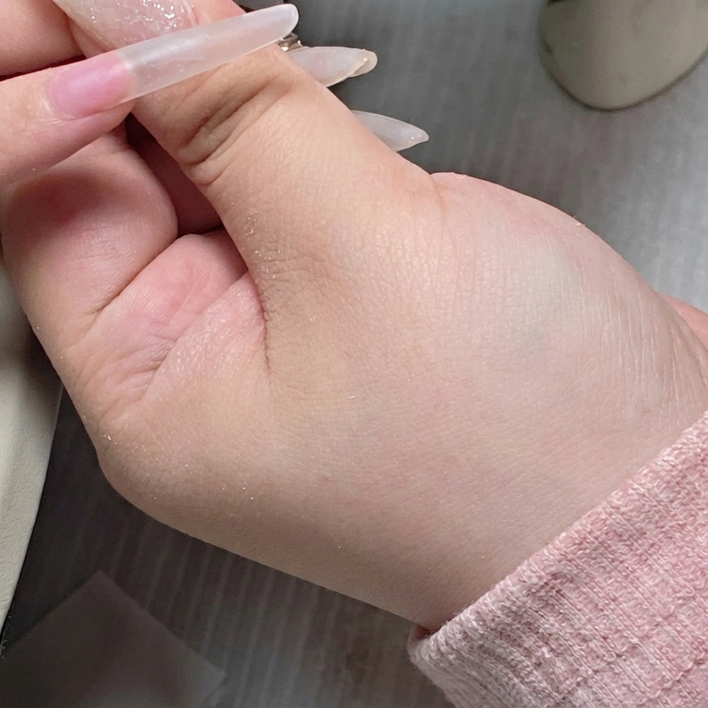 Il pennello di un flacone di gel che applica una base trasparente al centro dellunghia.