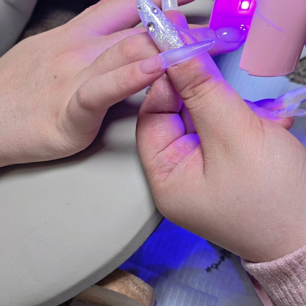 Una mini lampada UV/LED posizionata sopra lunghia per polimerizzare il secondo strato di builder gel.