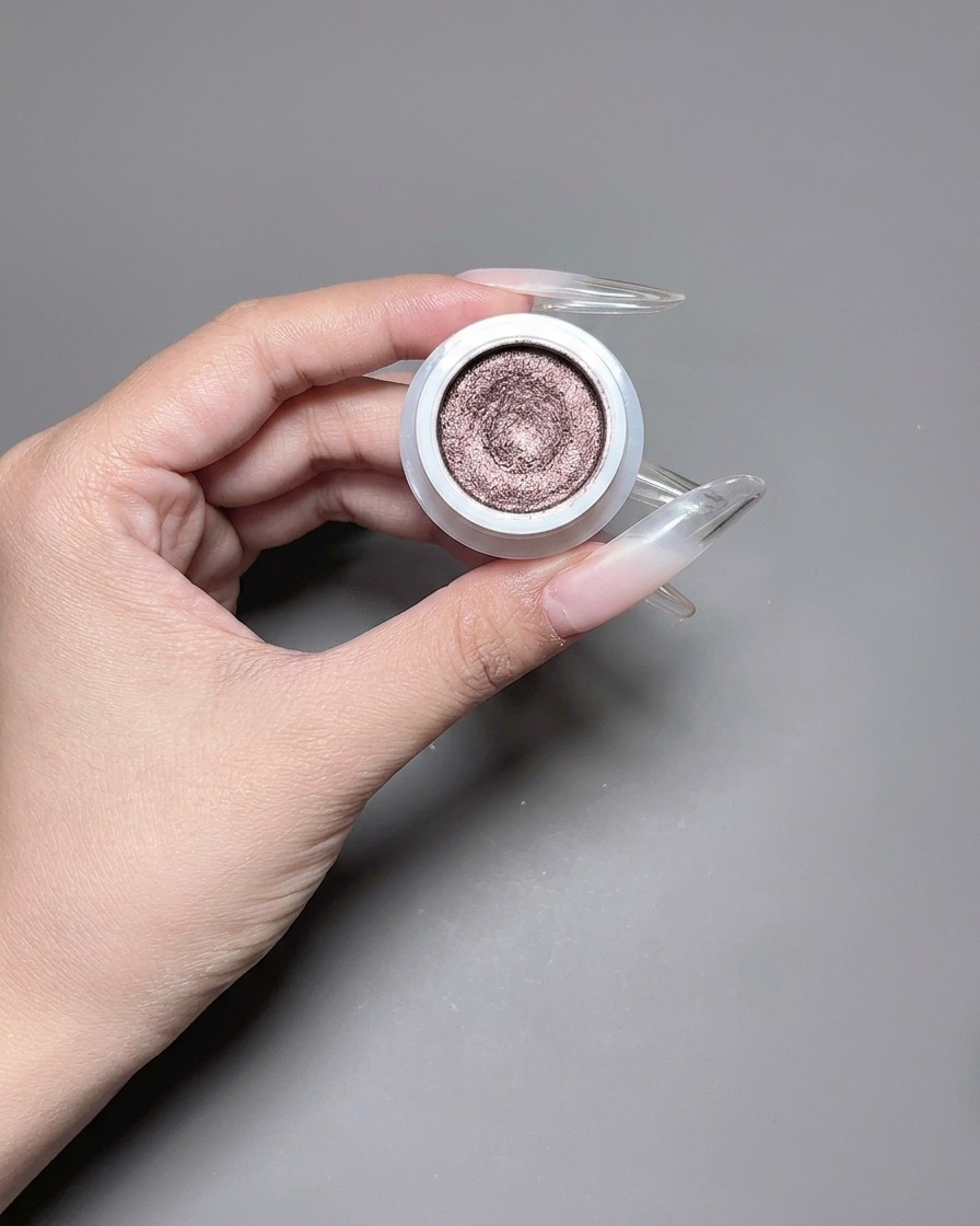 Un pennello stende uno smalto gel cat eye riflettente e scintillante su ununghia lunga.
