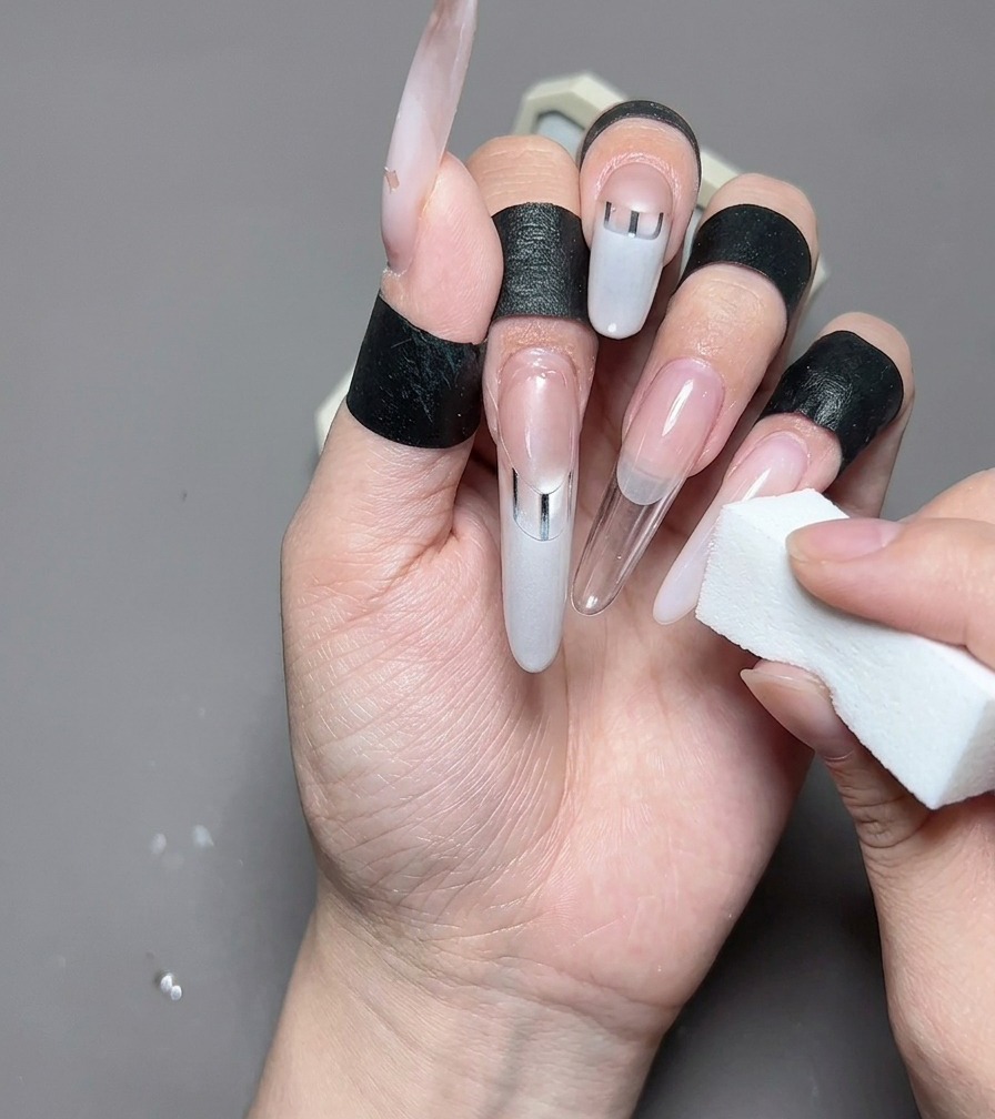 Primo piano di un pennello liner che disegna una french bianco latte su ununghia pulita a forma di mandorla.