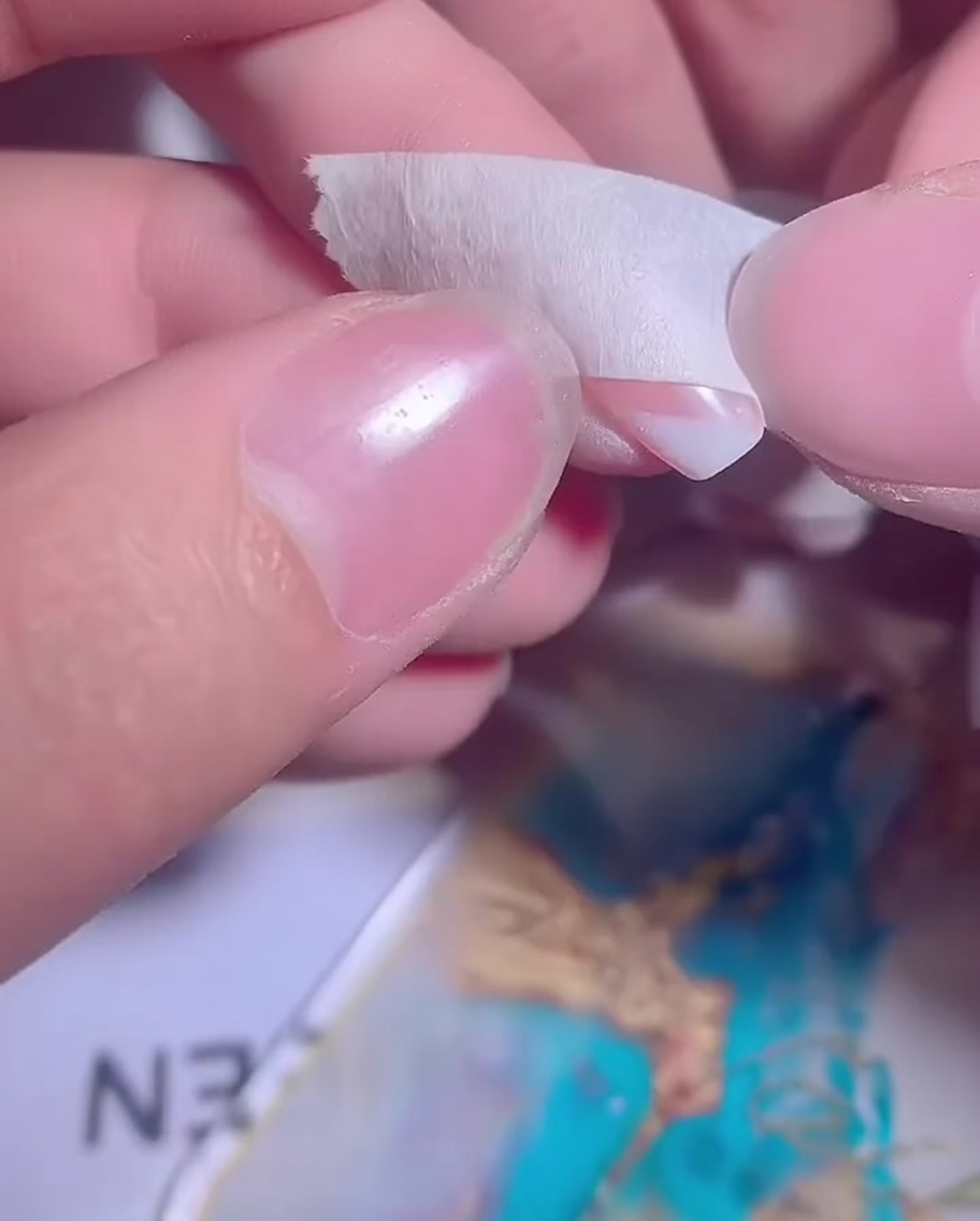 Ununghia con un ombré di gel bianco parzialmente applicato, preparata per un secondo strato.