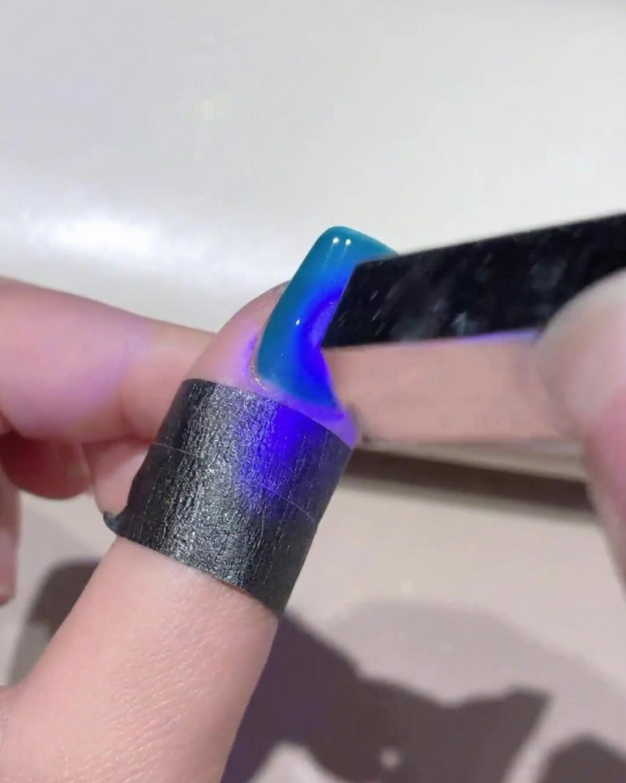 Mini lampada UV che illumina ununghia blu cat-eye per fissare il design.