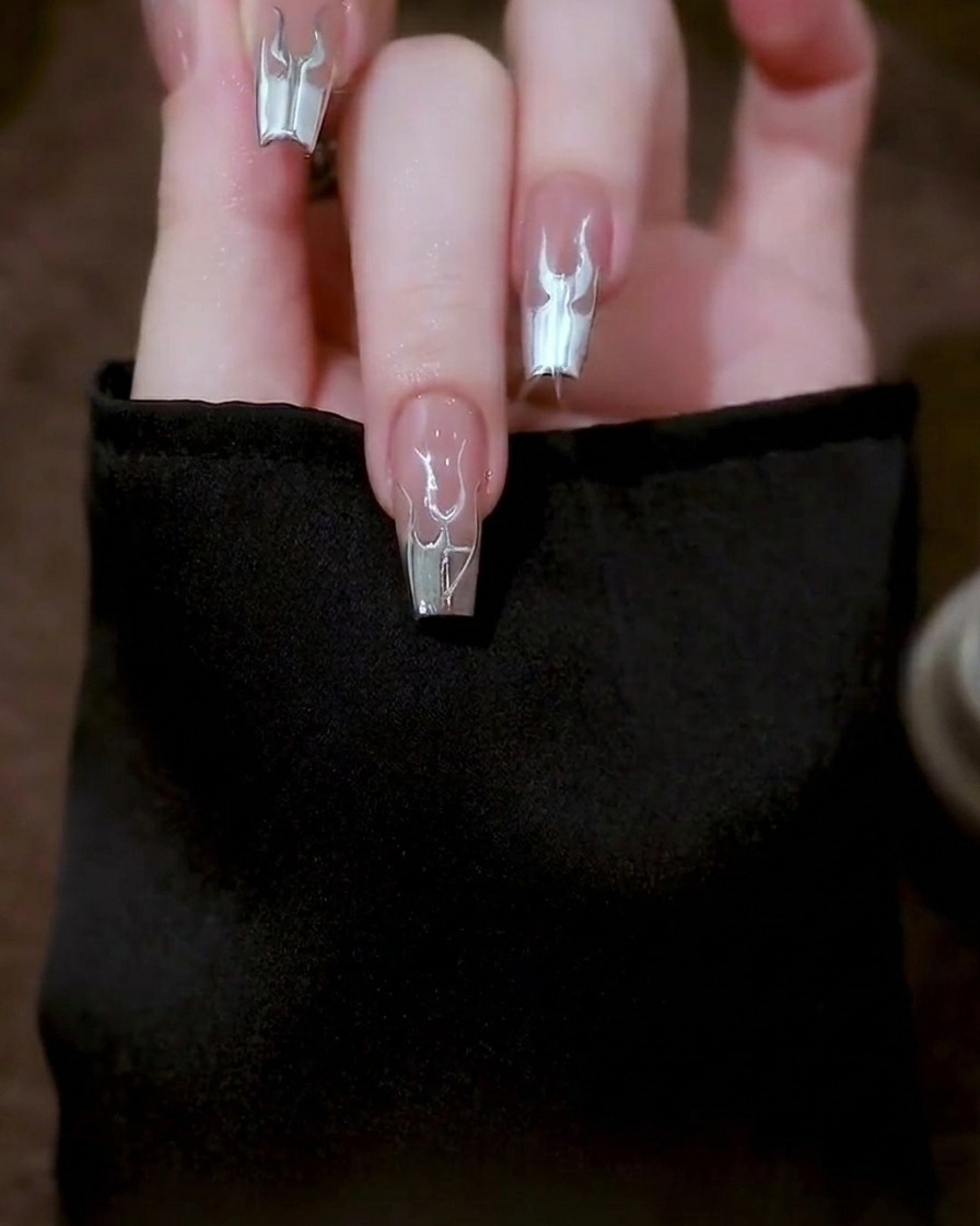 Primo piano che mostra il design finale delle fiamme argento dettagliato su una tip per unghie trasparente.