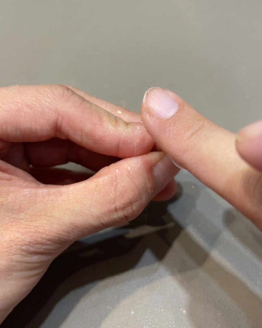 Un applicatore in spugna stende polvere a specchio iridescente su ununghia per un finish brillante.