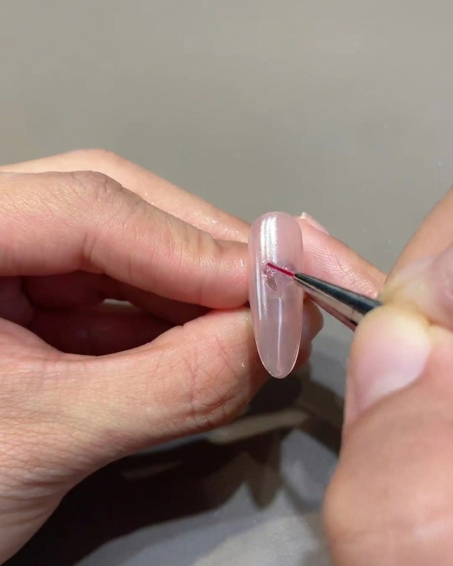 Un pennello liner sottile unisce meticolosamente i punti di gel per formare un cuore definito sullunghia.