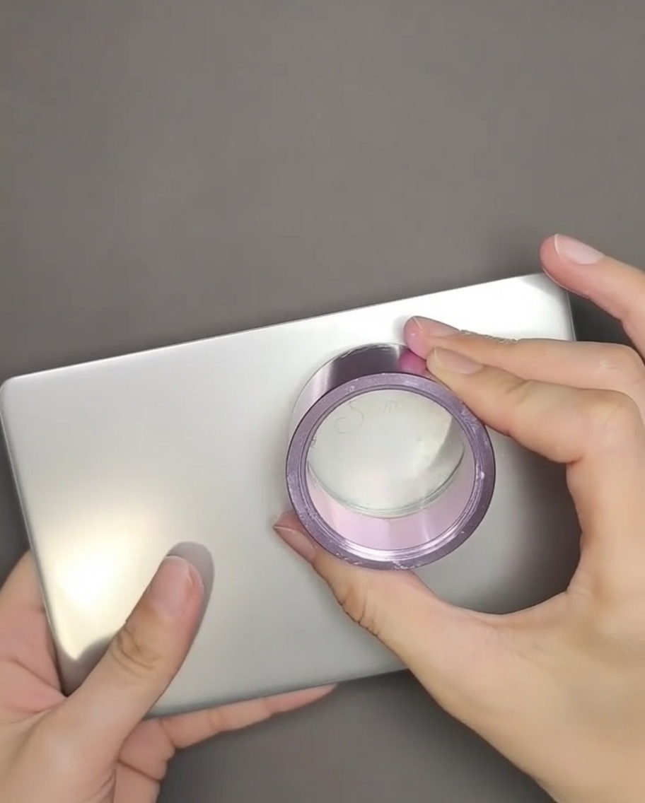 Uno stamper in silicone trasparente che preme su un design con testo inglese su una piastra per stamping in metallo.