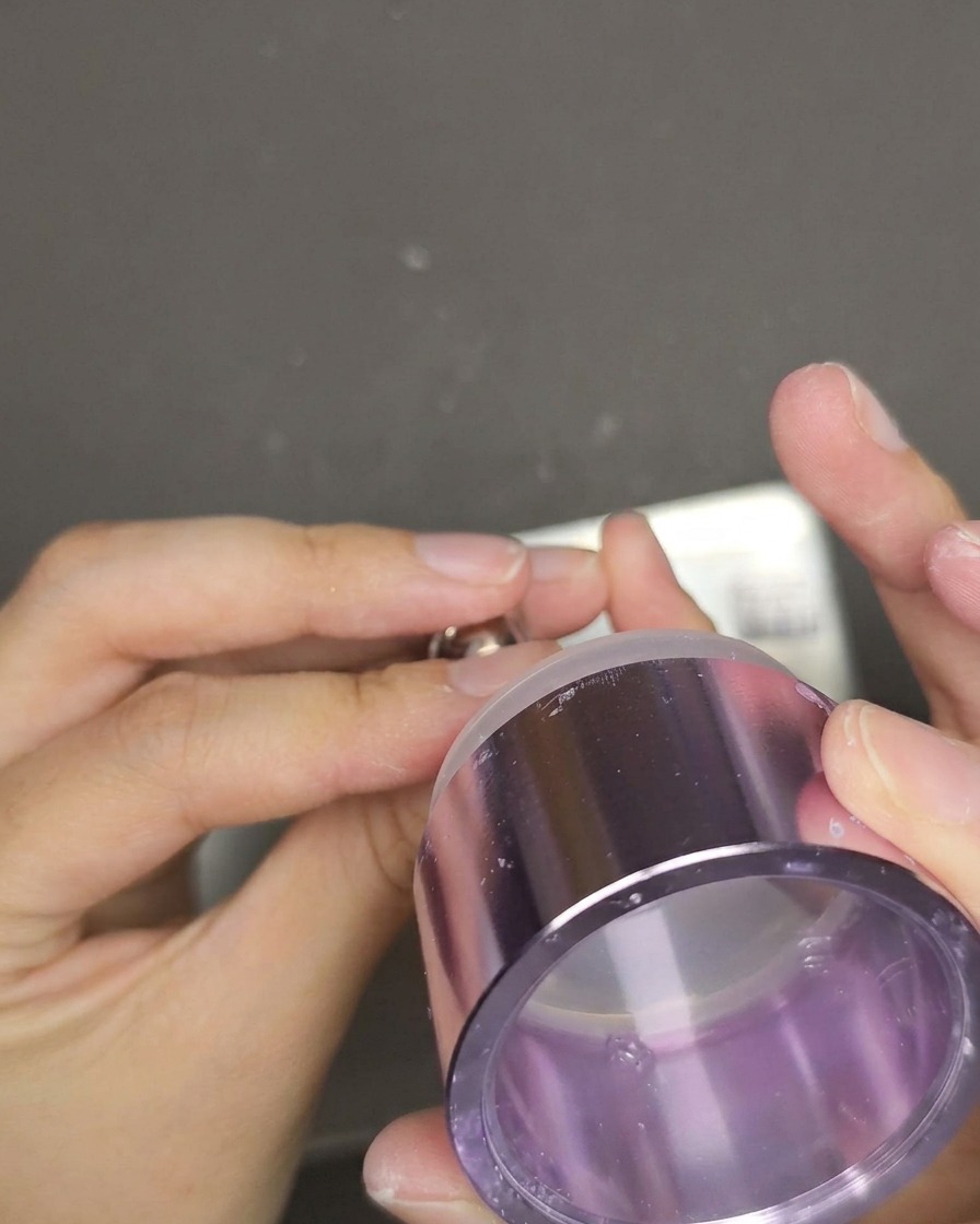 Uno stamper in gel trasparente che viene premuto su ununghia rosso cat eye per trasferire il design con testo inglese bianco.