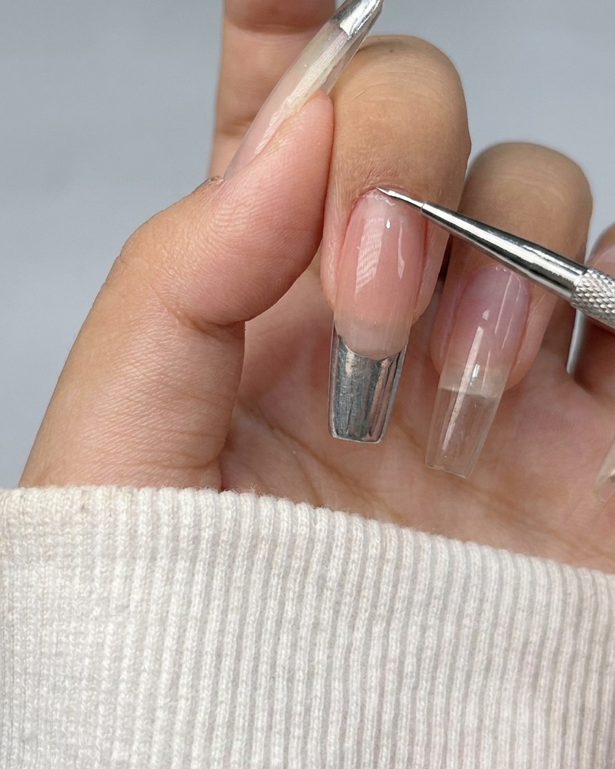Ununghia con una French tip che viene riempita con gel metallizzato argento brillante.