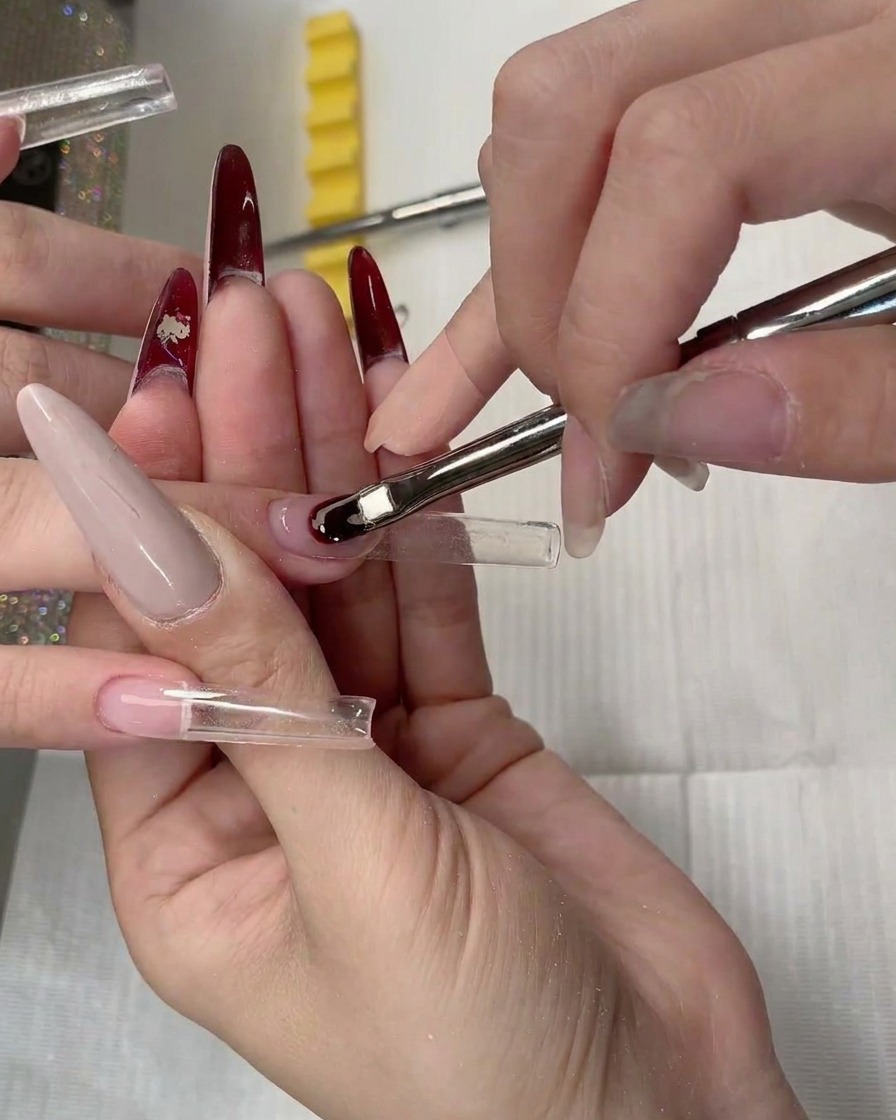 Primo piano di una nail form trasparente posizionata sotto la lamina ungueale naturale.