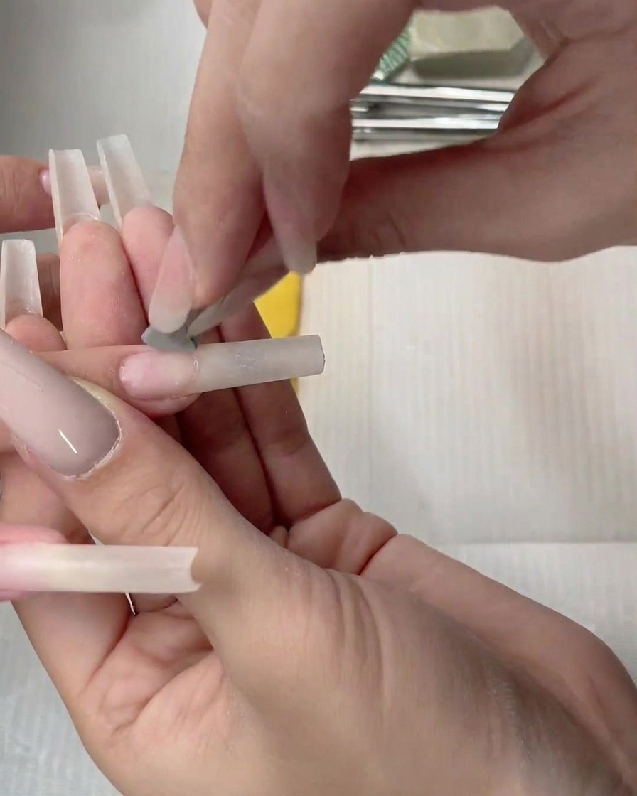 Un applicatore a spugnetta che picchietta il gel nude sul letto ungueale per diffondere il colore.