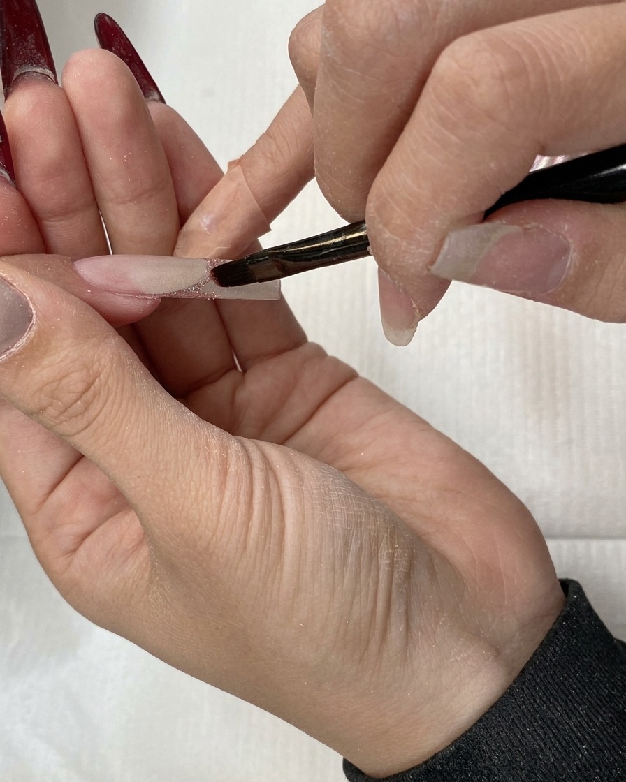 Un pennello piatto che trascina i glitter verso il basso per creare un effetto ombré.