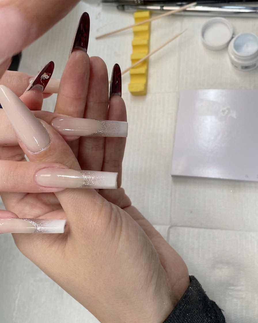 Primo piano di uno strumento in spugna utilizzato per picchiettare il gel bianco sulla punta di ununghia quadrata a tubo.