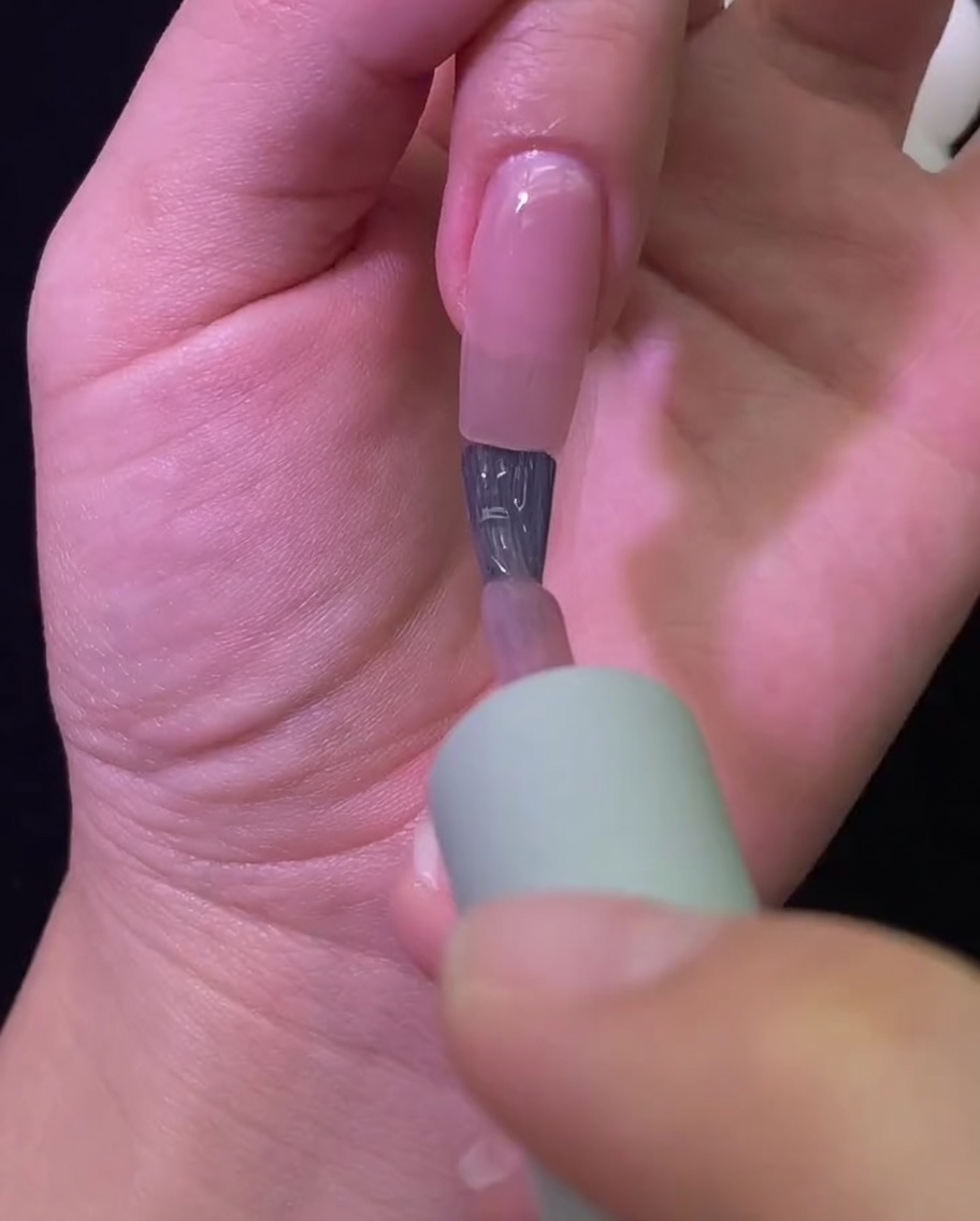 Una mano inserita allinterno di una lampada professionale UV/LED mentre il colore dellunghia asciuga.