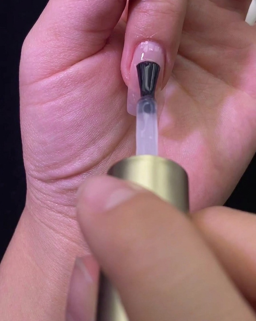 Un pennello che stende un top coat opaco su ununghia color nude, trasformandone la finitura.