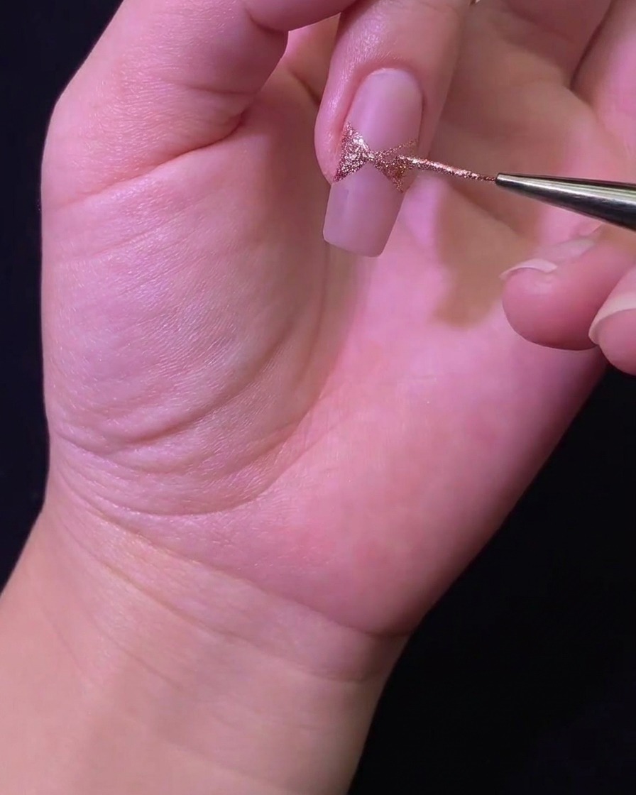 Dettaglio di un pennello liner che riempie la forma del fiocco glitterato sulla superficie dellunghia.