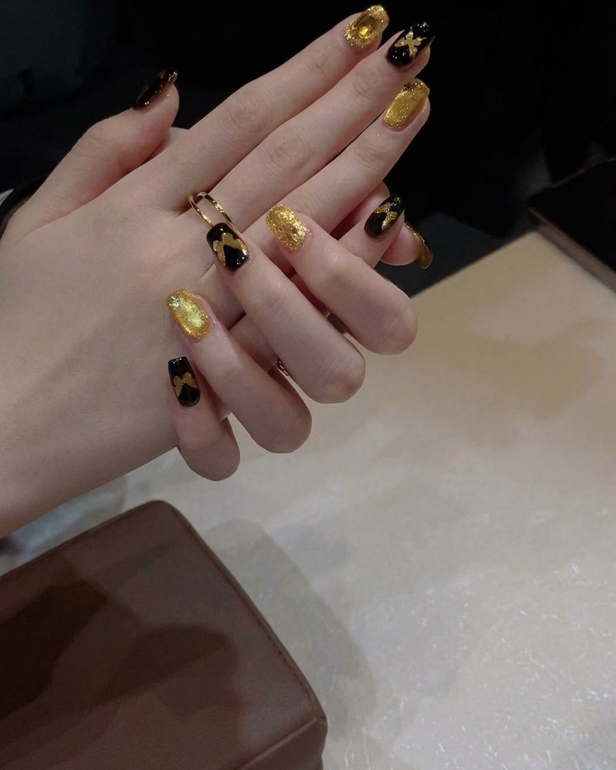 Un pennello da gel applica uno strato di smalto cat-eye oro scintillante su ununghia con base nera.