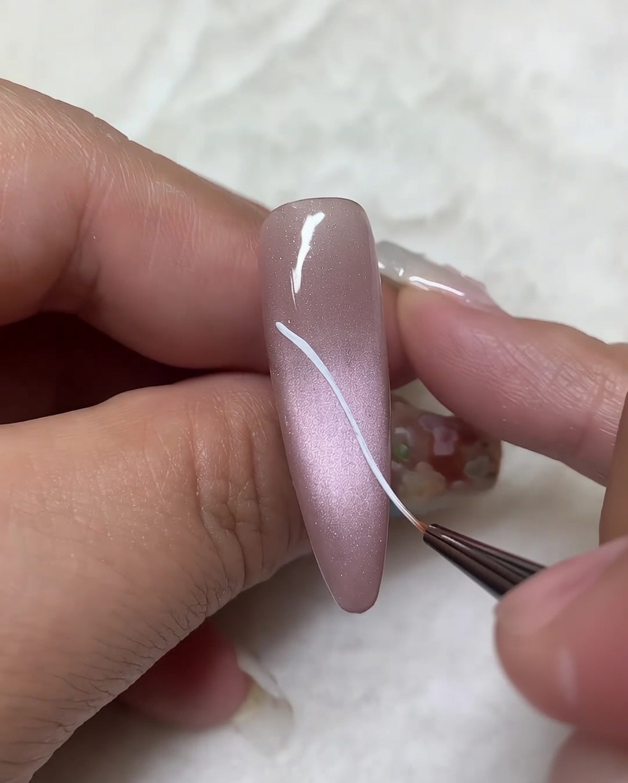 Un pennello liner che aggiunge linee curve ai contorni diagonali precedenti per completare la forma dellala superiore.