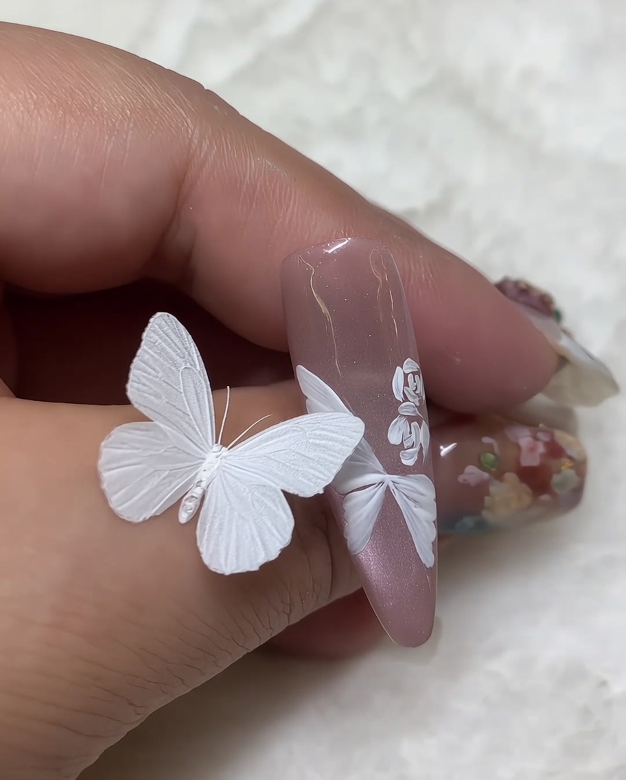 Dettaglio macro di un design nail art completato con una rosa bianca in cui il centro è stato intensificato usando piccole e dense pennellate bianche.