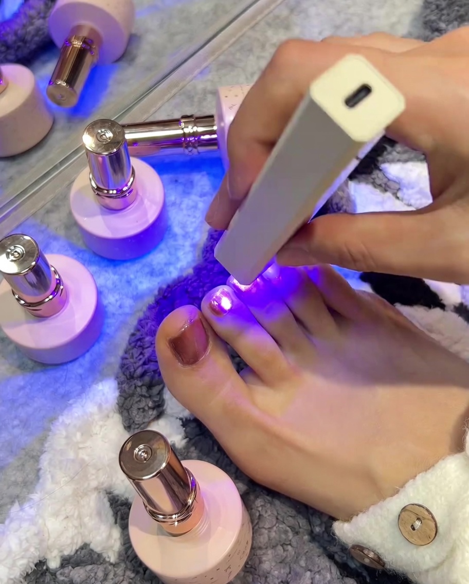 Lampada UV/LED sopra ununghia rosa che emette luce viola per fissare il colore.