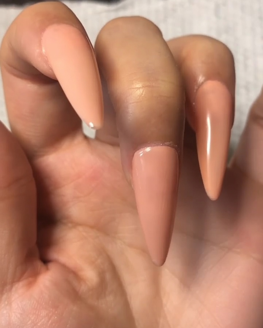 Un pennello per unghie che applica un sottile strato di top coat sullo smalto nude dellindice.