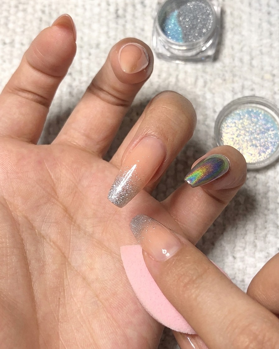 Applicazione di polvere olografica picchiettando sulla punta di un anulare curato.