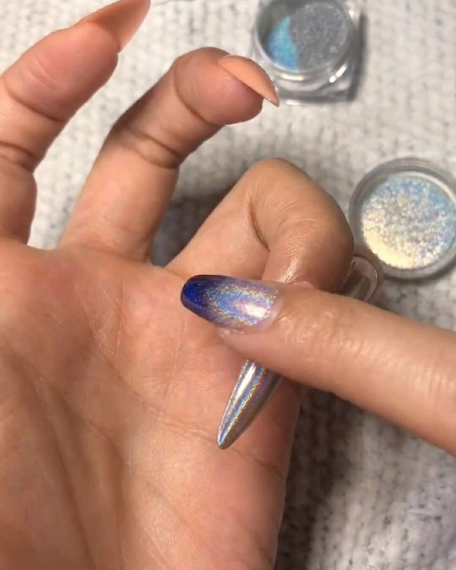 Un primo piano che mostra la polvere olografica sfumata sullunghia per un look ombré.