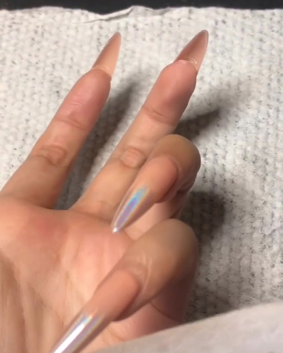 Una mano che usa un piccolo buffer per limare il bordo anteriore di un indice.