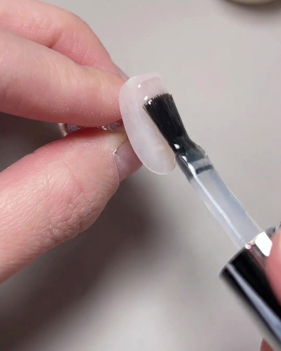 Una mano posizionata allinterno di una lampada UV/LED per la polimerizzazione.