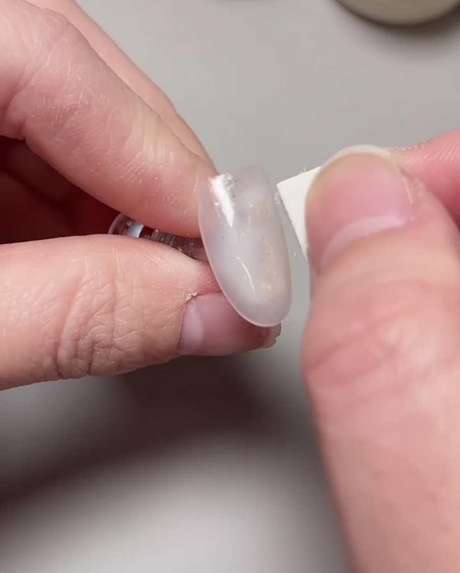 Un pennello applica un secondo strato di smalto gel rosa lychee per aumentare lopacità.