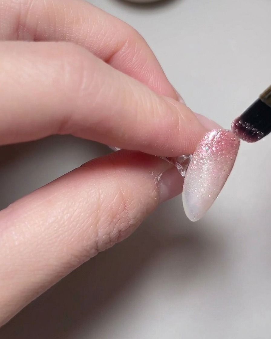 Una mano posizionata allinterno di una lampada con smalto gel cat eye in fase di polimerizzazione sulle unghie.