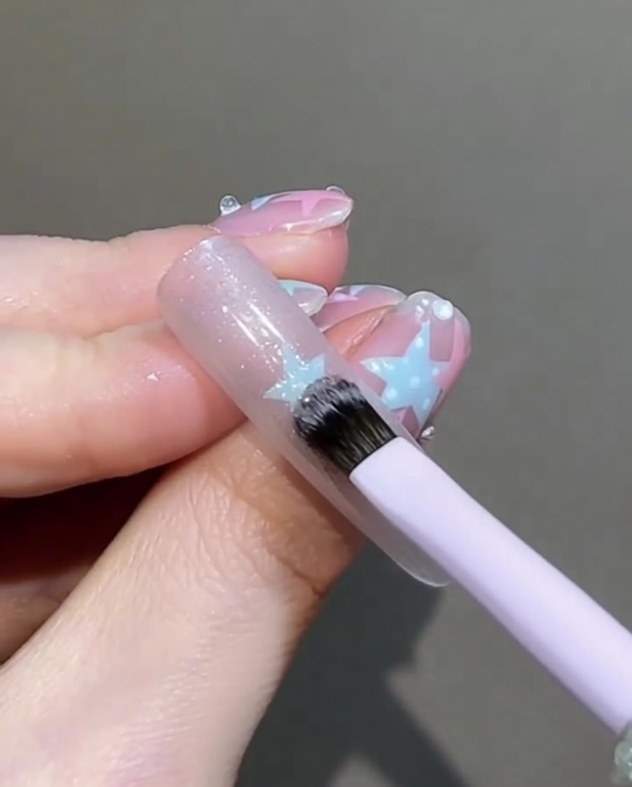 Un piccolo pennello piatto che tampona e leviga delicatamente il gel cat-eye bagnato sullunghia.