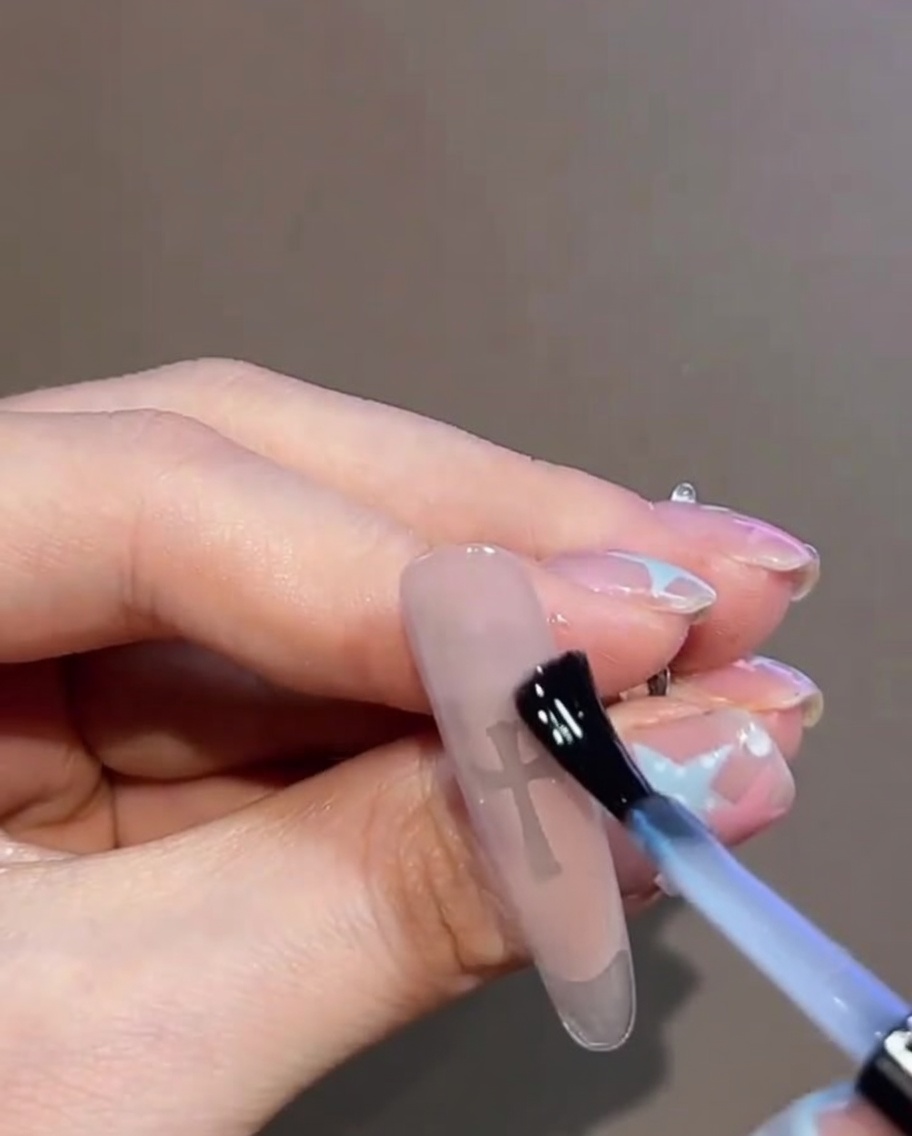 Dettaglio di un top coat trasparente applicato sopra lunghia finita con croce e strass.