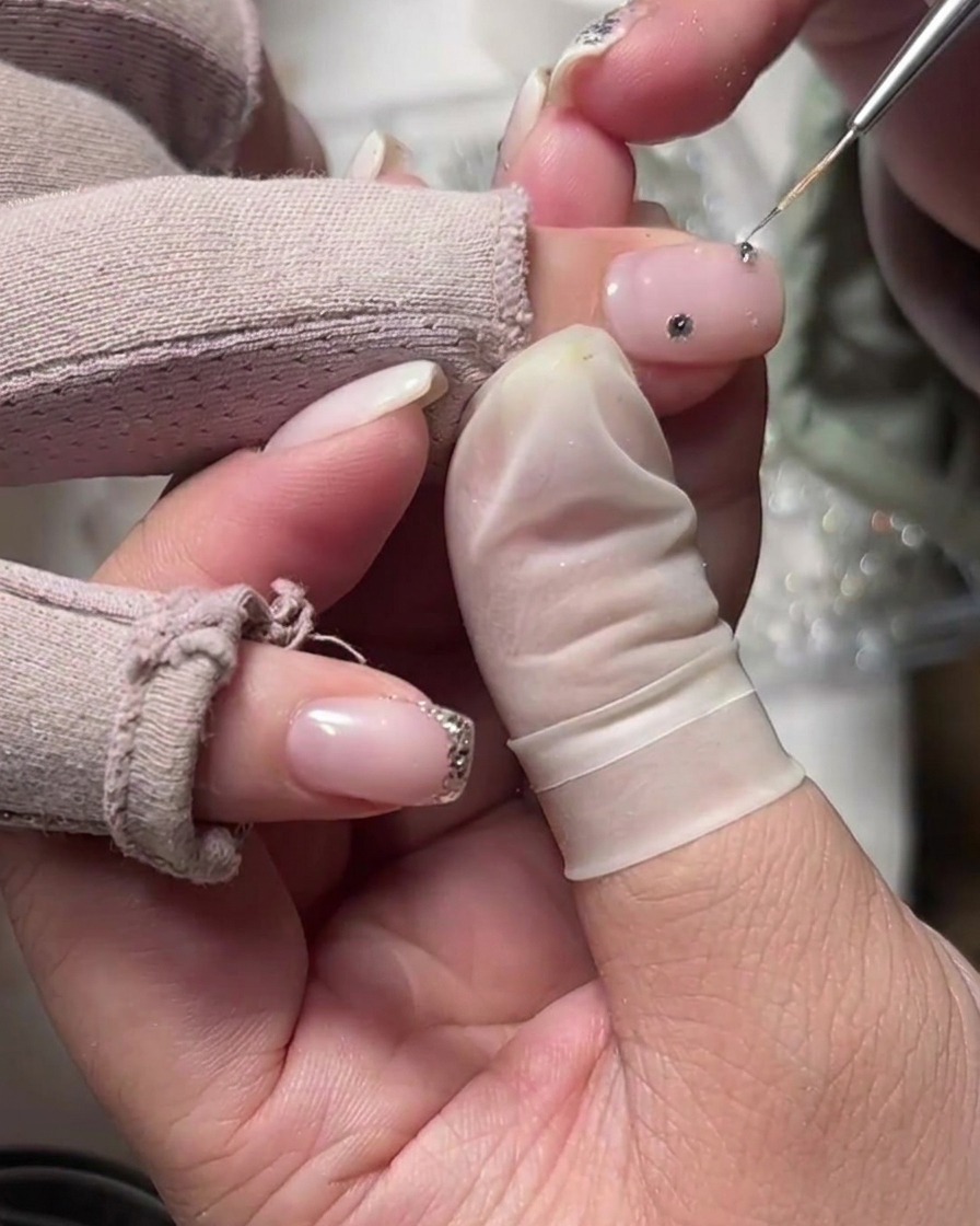 Un applicatore posiziona uno strass singolo sulla base milky vicino alla cuticola.