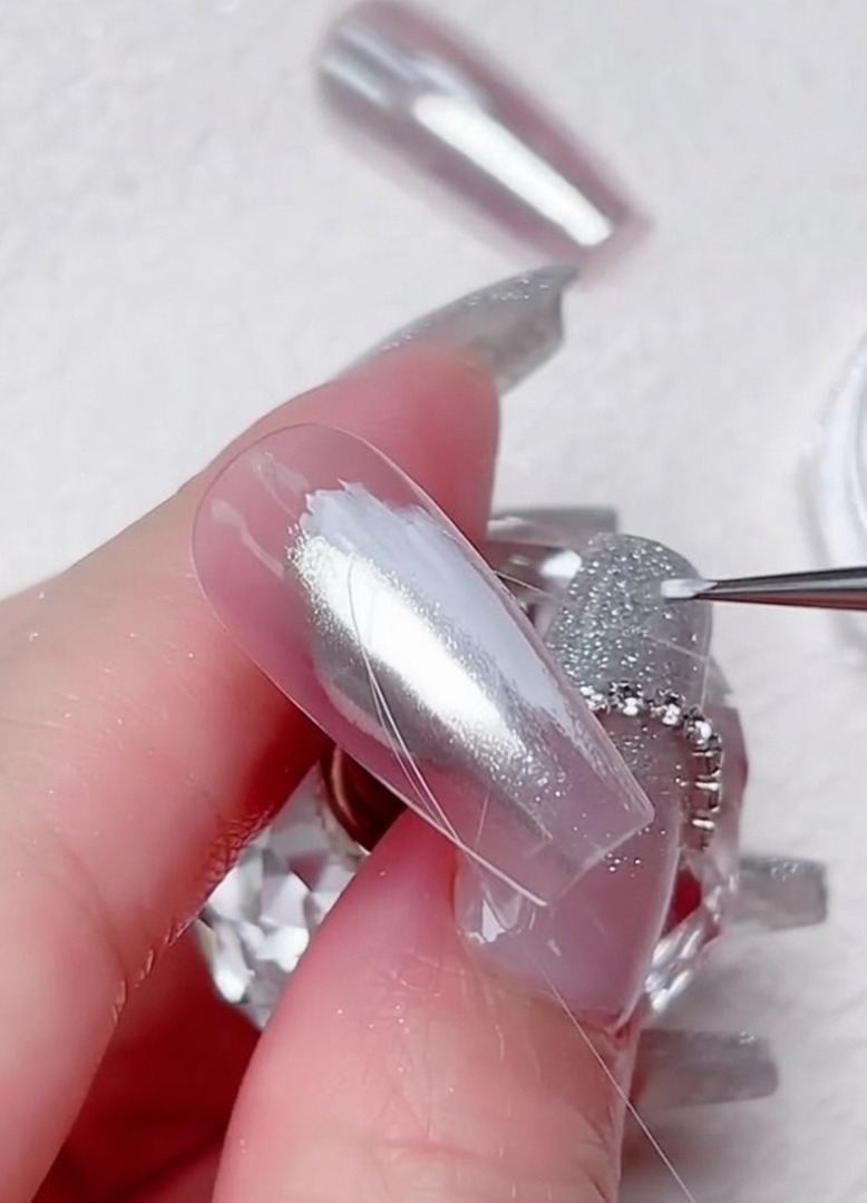Un pennello liner sottile disegna linee di gel trasparente in un motivo diagonale.