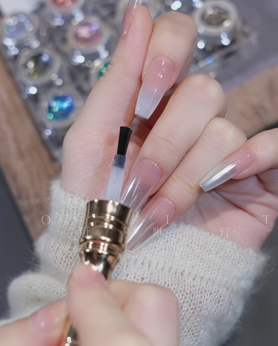Un pennello che applica il top coat trasparente sullunghia sfumata completata.