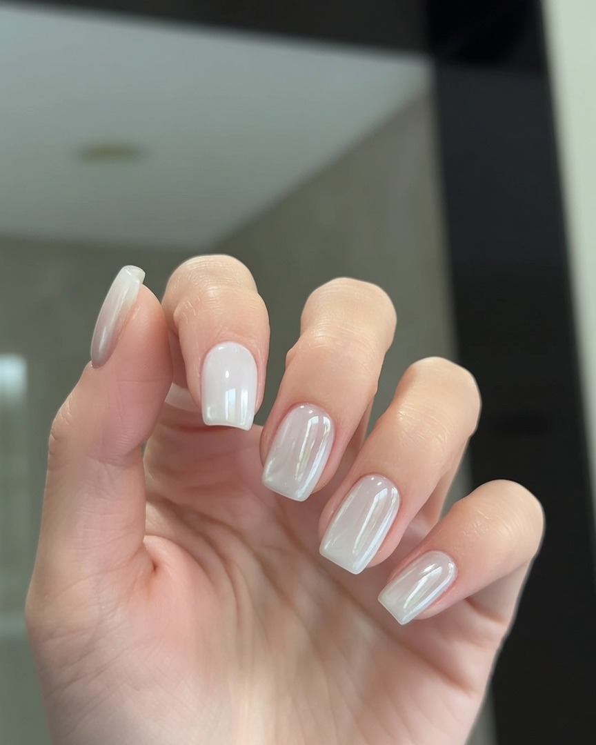 Un pennello che applica uno strato di top coat trasparente sopra unghie con finitura pearl chrome.