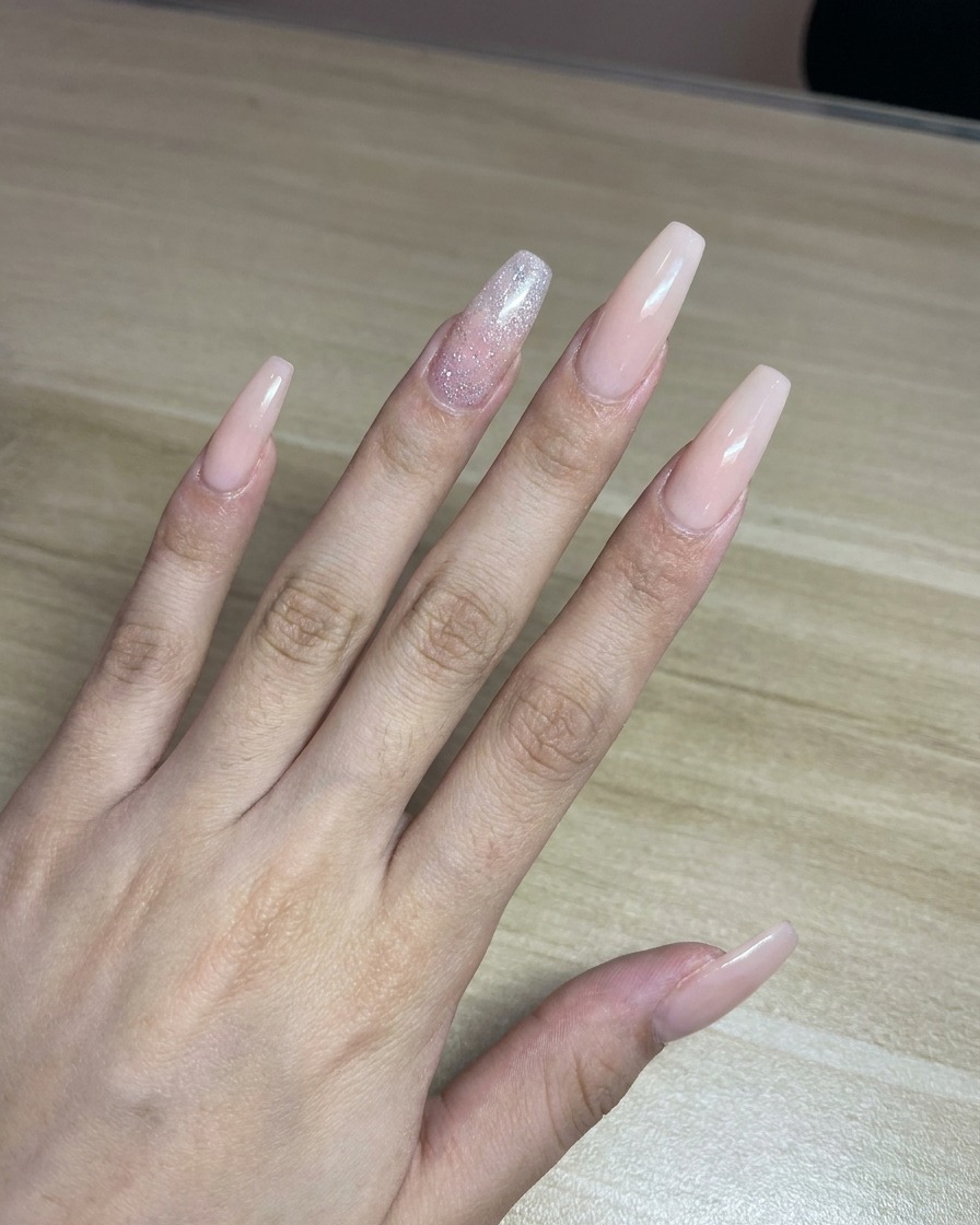 Un tecnico che spruzza colore rosa da un aerografo su un foglio di carta bianco come prova prima dellapplicazione sulle unghie.