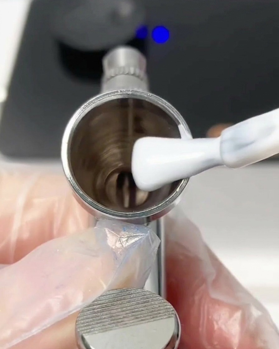 Un pennello che aggiunge una goccia di gel bianco nel serbatoio dellaerografo.