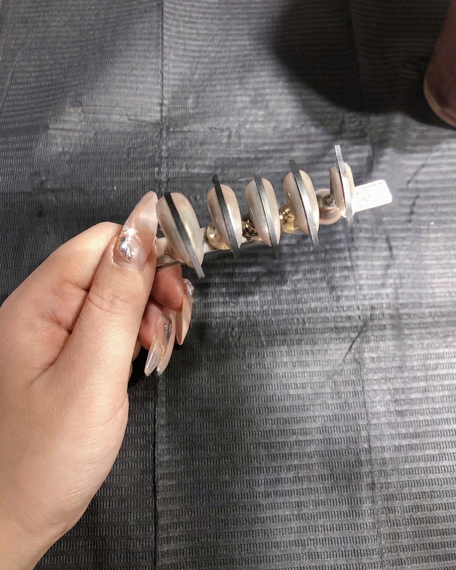 Una pistola per airbrush che applica la prima mano di spray gel bianco al secondo set di unghie.