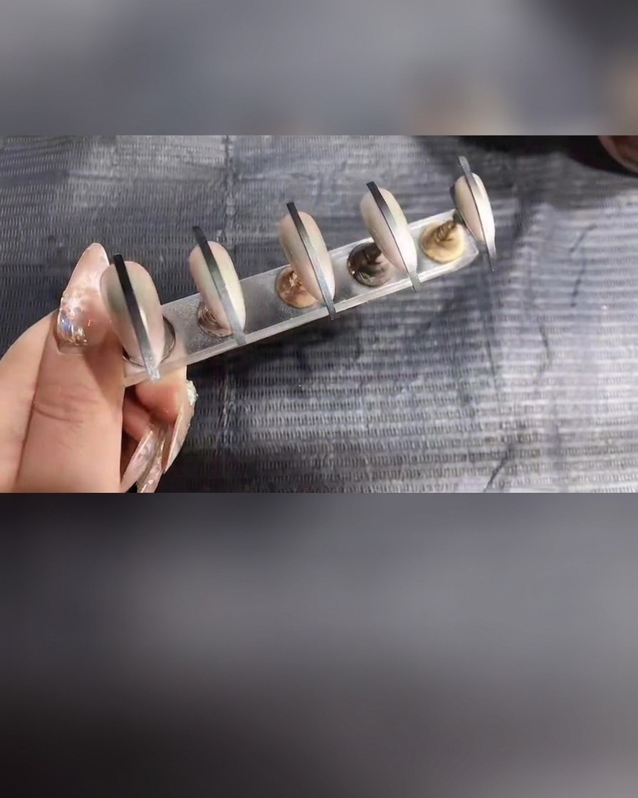 Primo piano delle unghie sul supporto che ricevono unultima leggera applicazione di spray gel.